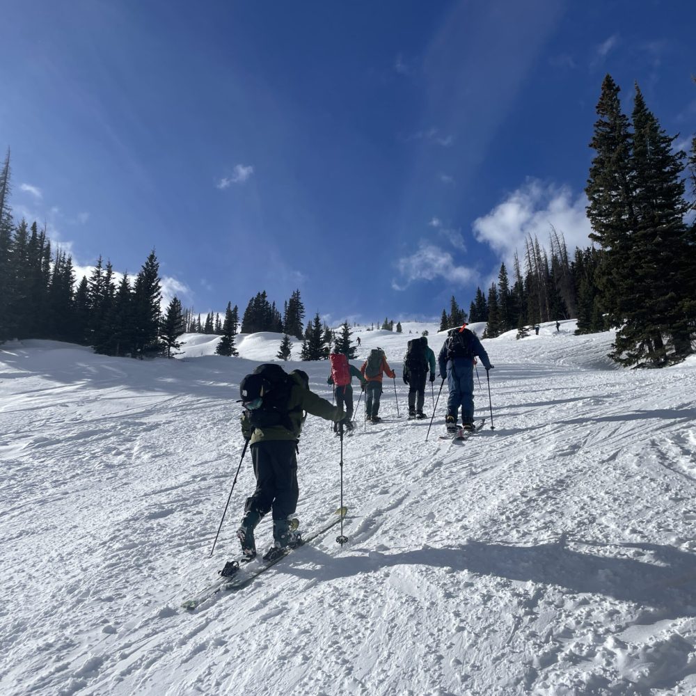 AIARE Level 1 participants skiing uphill during an avalanche training course